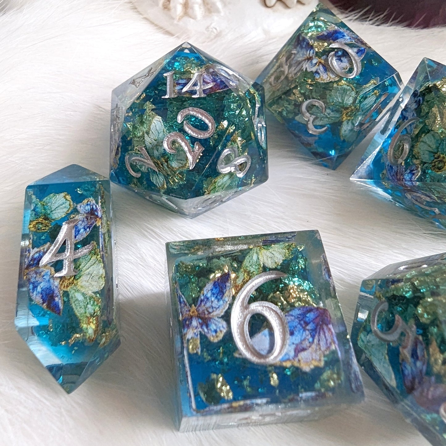 Butterfly Realm DnD Dice Set with blue, gold, and purple butterfly design on white fur background, featuring silver numbers.