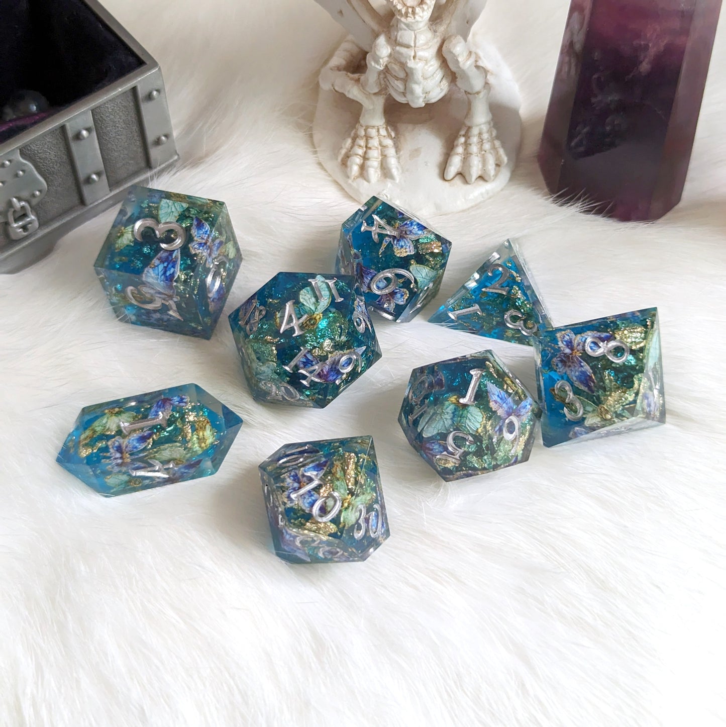 Butterfly Realm DnD Dice Set with blue, gold core, and purple butterflies on white fur background, includes unique crystal-shaped D4.