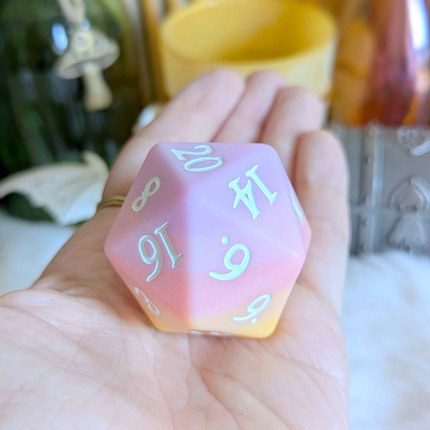 Sorbet Sunset Large D20 die with pink to orange ombre and white numbers in a hand, enhancing tabletop gaming experience.