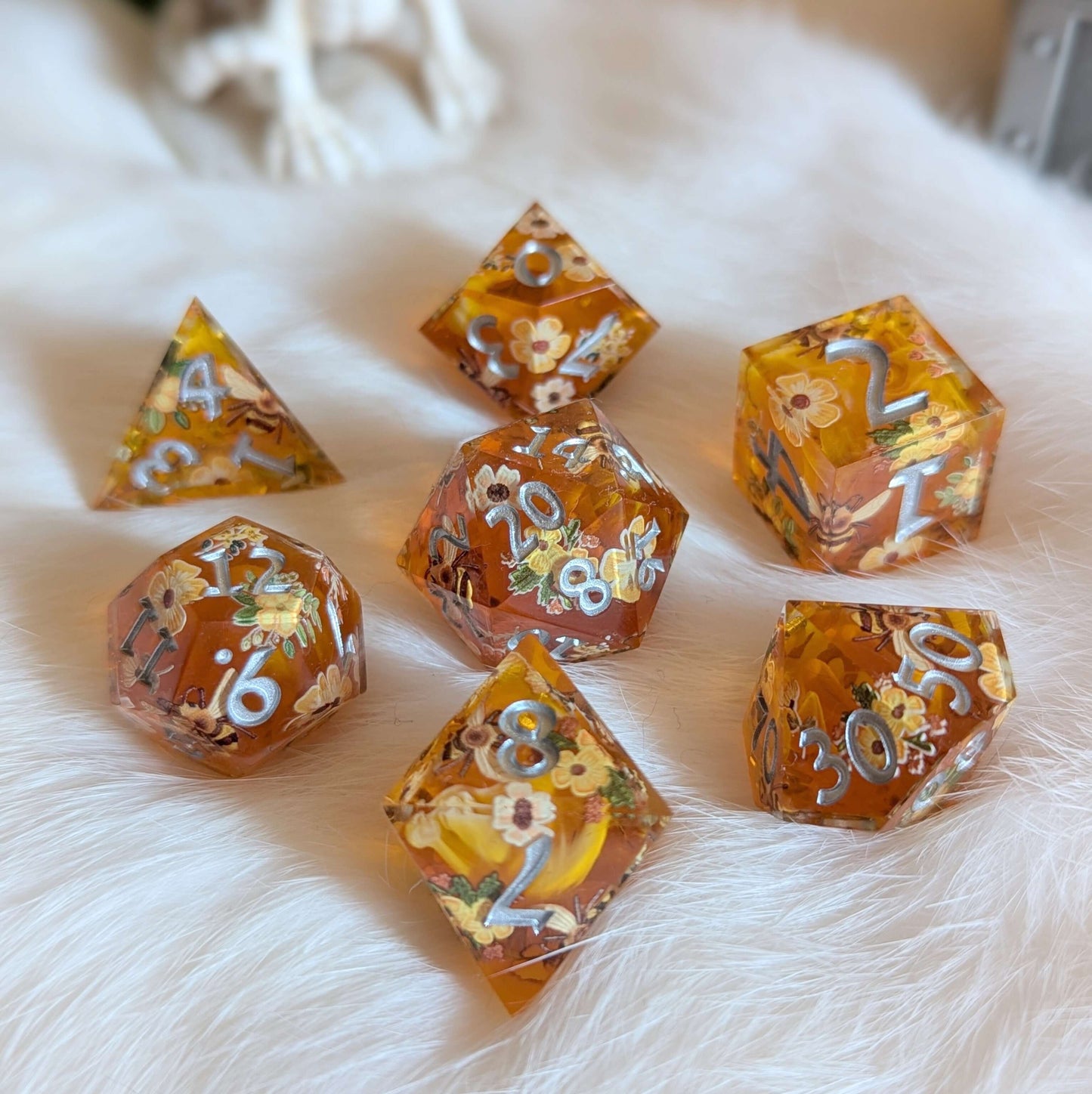 Honey Blossom Sharp-Edge Dice Set with floral and bee designs on soft fur background.