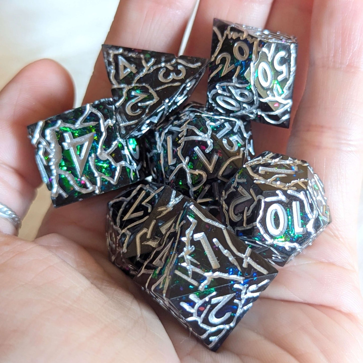 Hand holding Stormlight Surge Sharp-Edged Dice Set with silver lightning cracks and shimmering interior swirl.