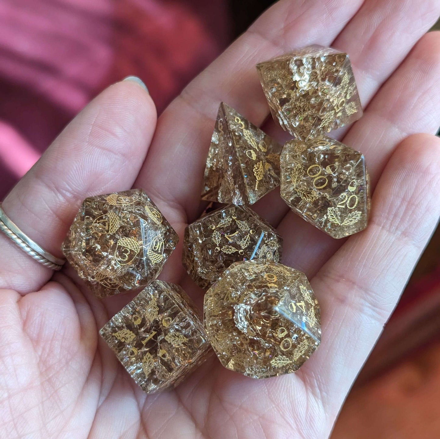 Hand holding Acorn and Oak Brown Lightning glass dice set featuring intricate acorn and oak leaf designs for tabletop games.