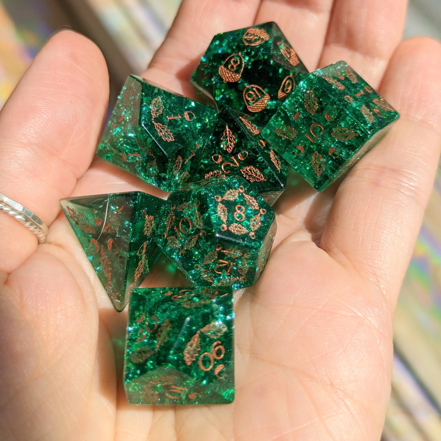 Green Lightning Glass Dice Set with acorn and oak leaf designs held in hand, perfect for gaming druids and dungeon quests.
