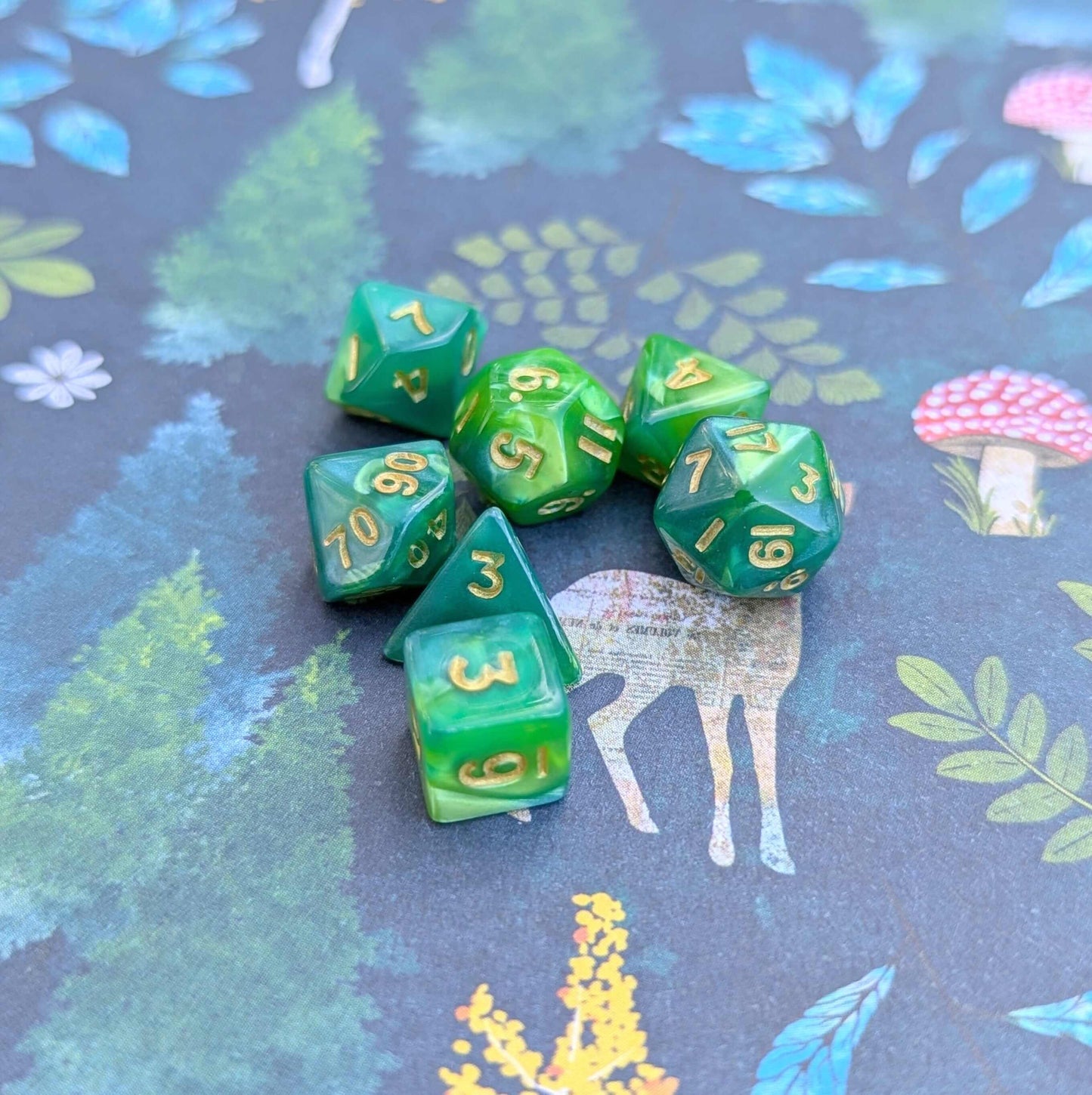 Archer's Mini Dice Set, pearly green TTRPG dice with gold numbers on a whimsical forest-themed background.
