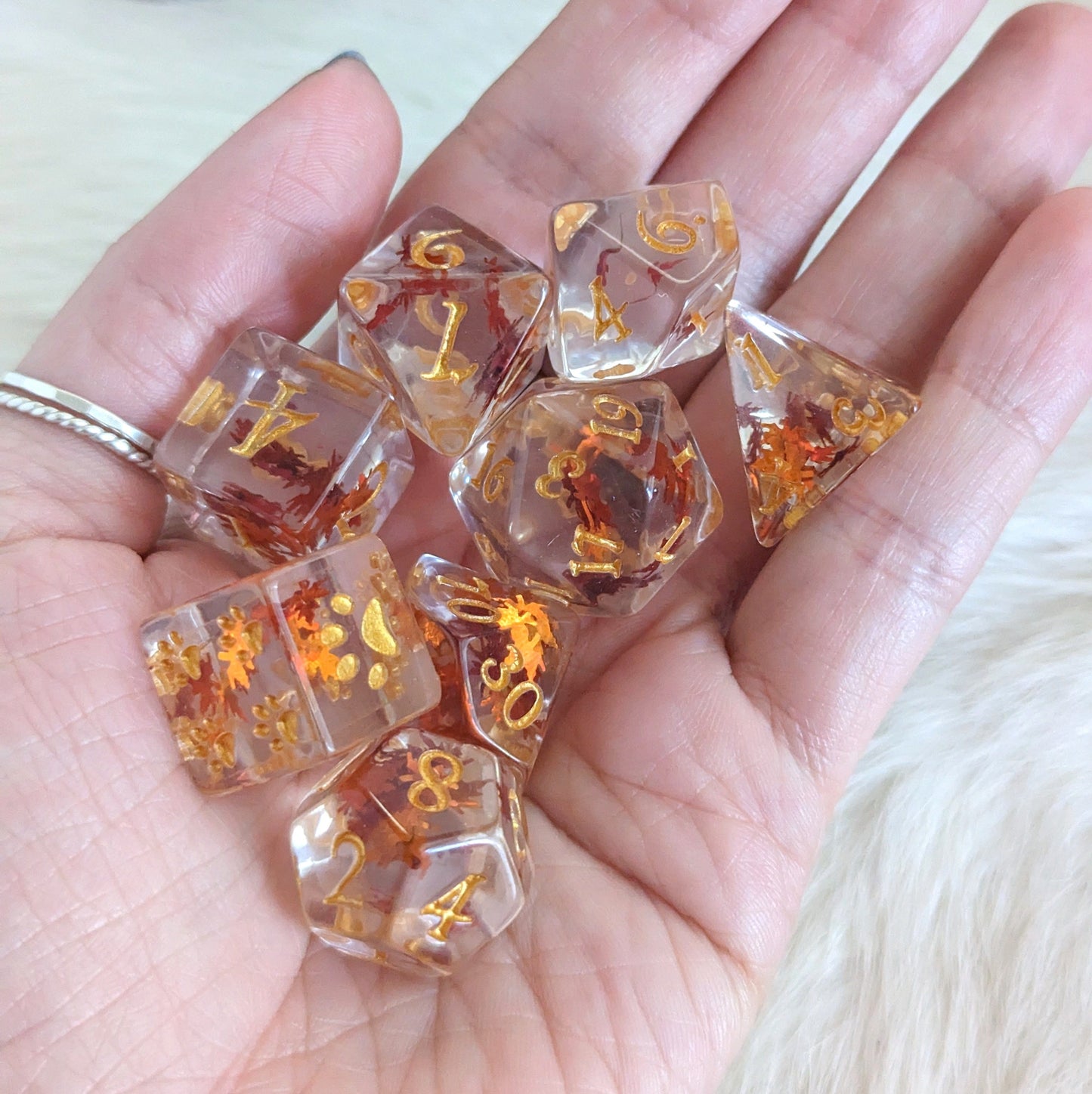 Autumn Leaf Dice Set with orange leaf glitter, 8 pieces for Dungeons & Dragons, shown in a hand. Fennek and Finch exclusive design.