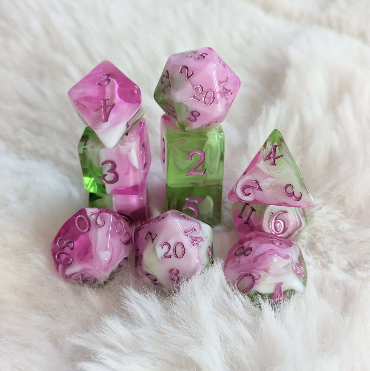 Bardic Inspiration Dice Set with pink, white, and green TTRPG dice featuring magenta numbers on a soft background.