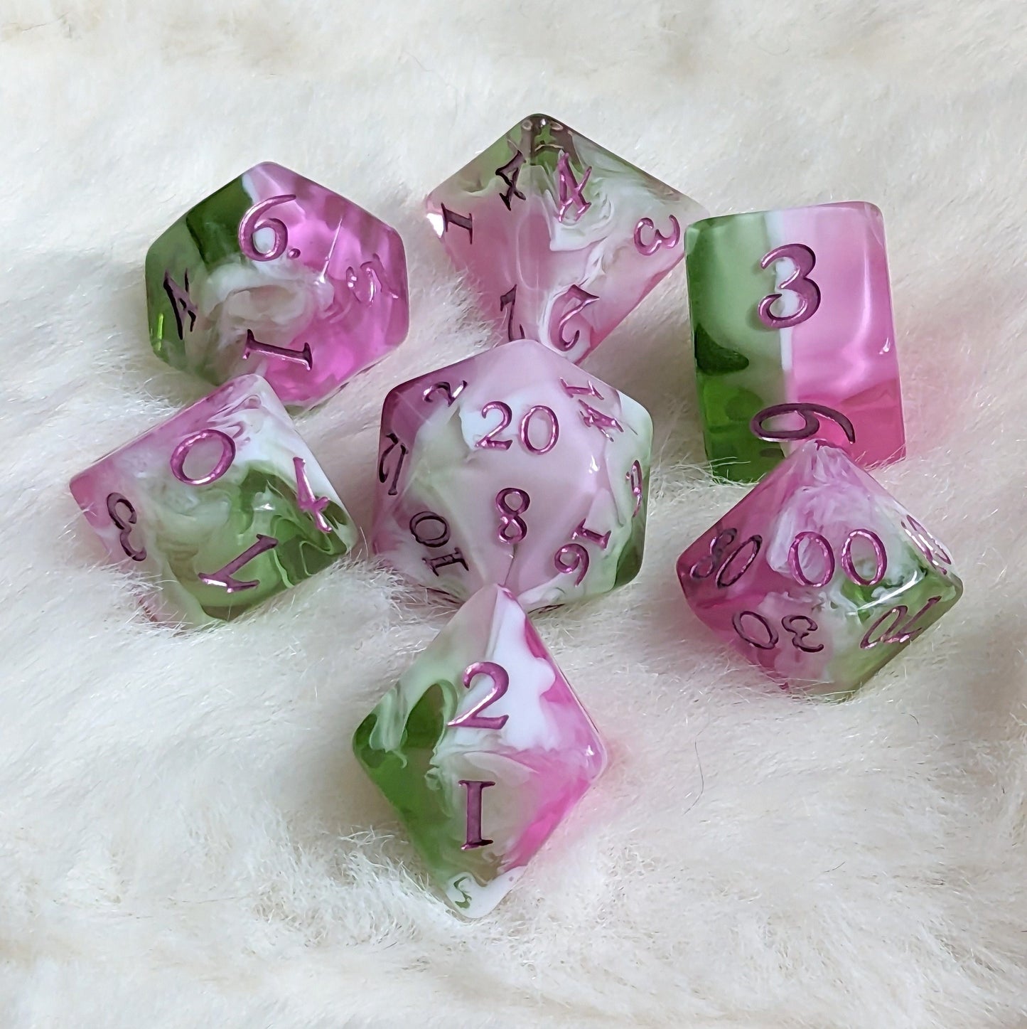 Bardic Inspiration Dice Set in pink, white, and green with metallic magenta numbers on a soft fur background.