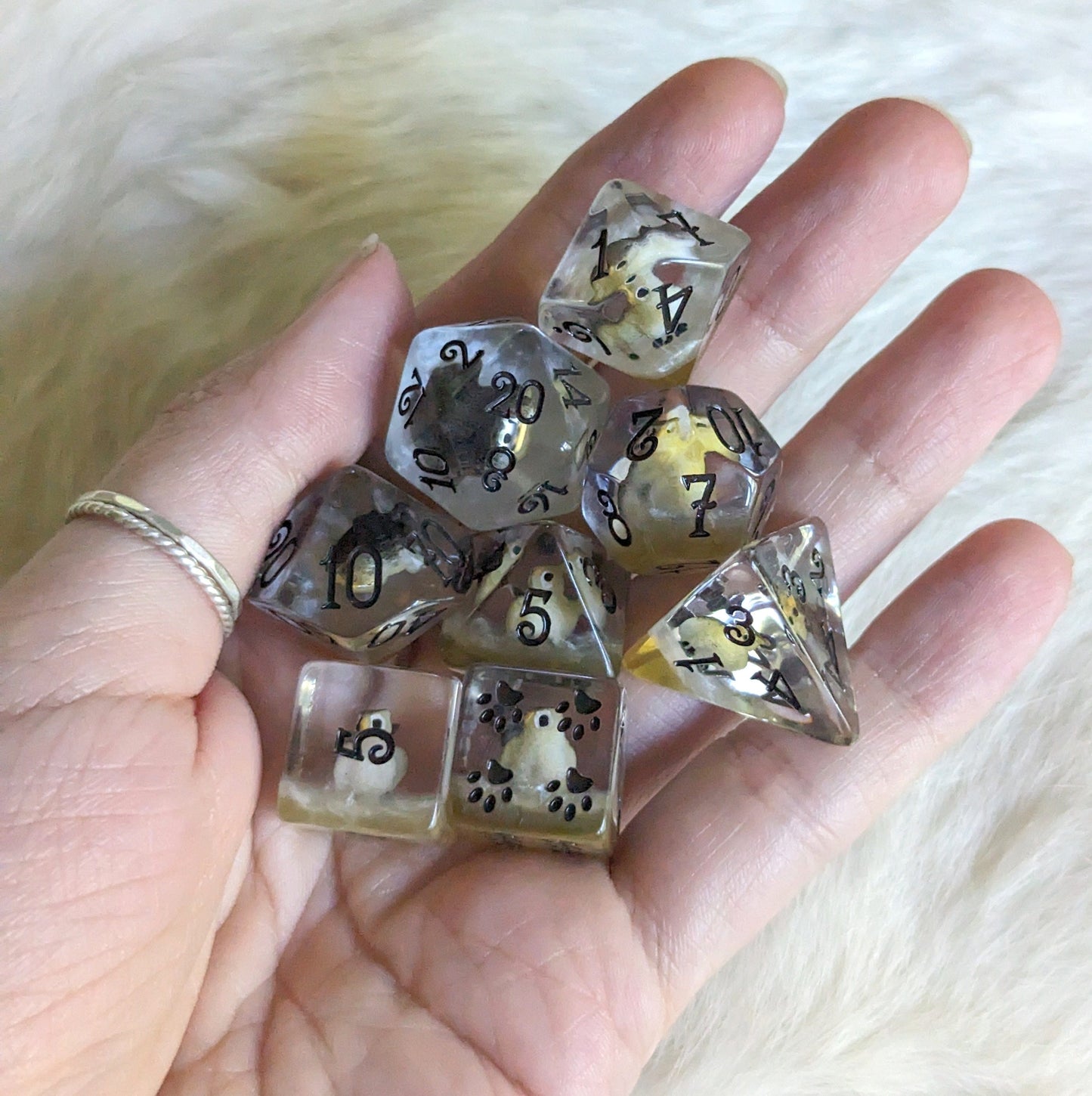 Hand holding Barn Owl Dice Set with mini owls in clear resin, featuring silver and brown layers, custom font, and paw counters.