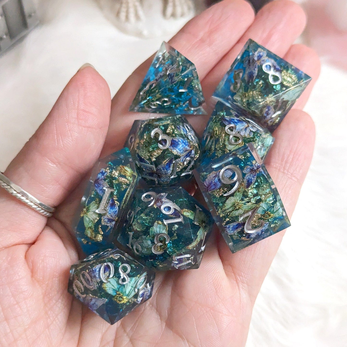 Hand holding Butterfly Realm DnD Dice Set with blue, gold, and purple butterfly details, featuring a crystal-shaped D4 die.