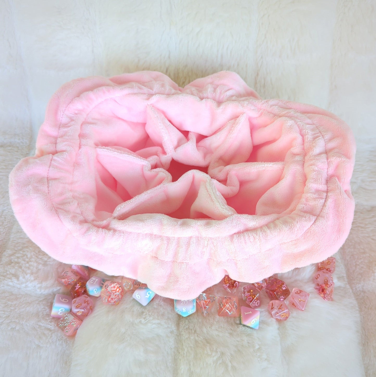Pink cherry blossom dice bag with multiple pockets, featuring plush fabric and surrounded by colorful dice.