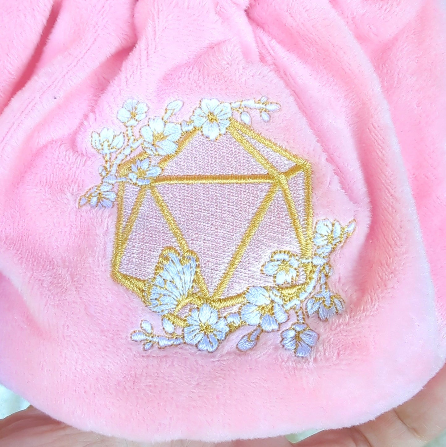 Pink cherry blossom dice bag with embroidered D20 design and floral details on plush fabric.