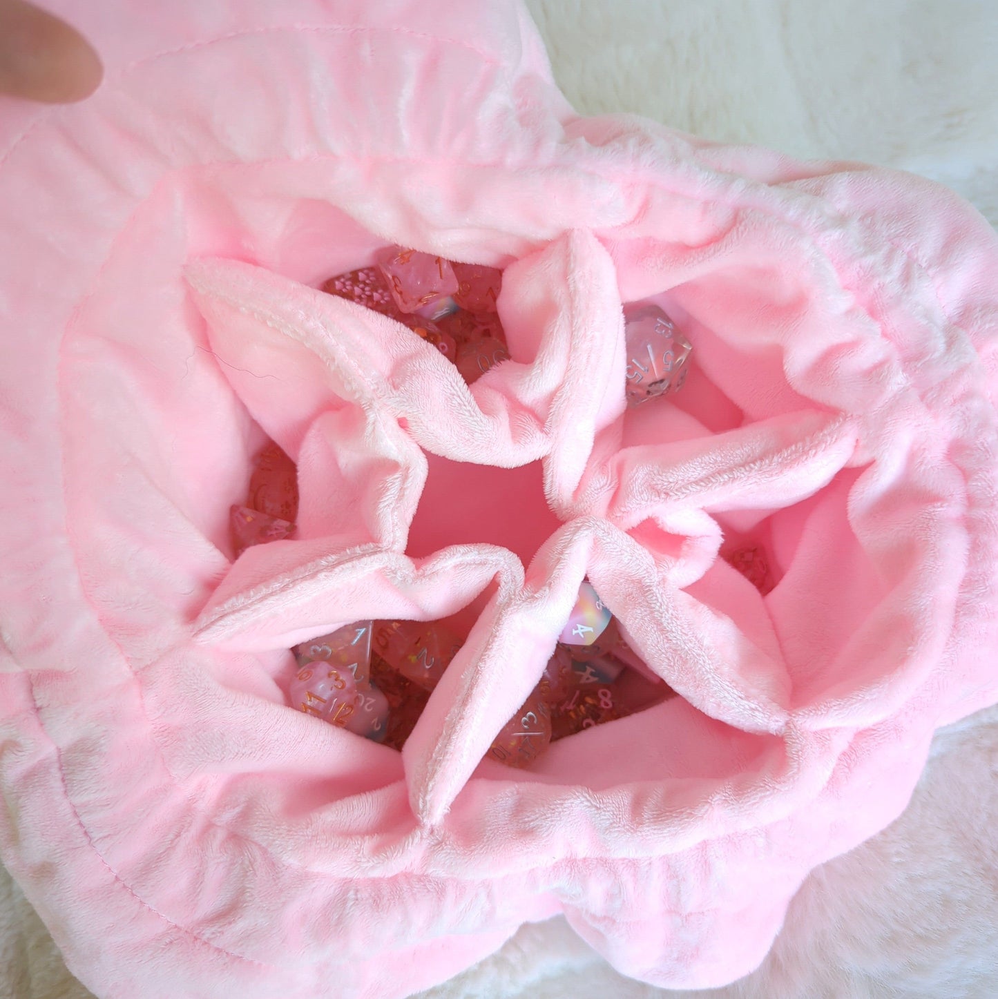Pink multi-pocket dice bag with cherry blossom design, showcasing plush fabric and spacious interior filled with colorful dice.