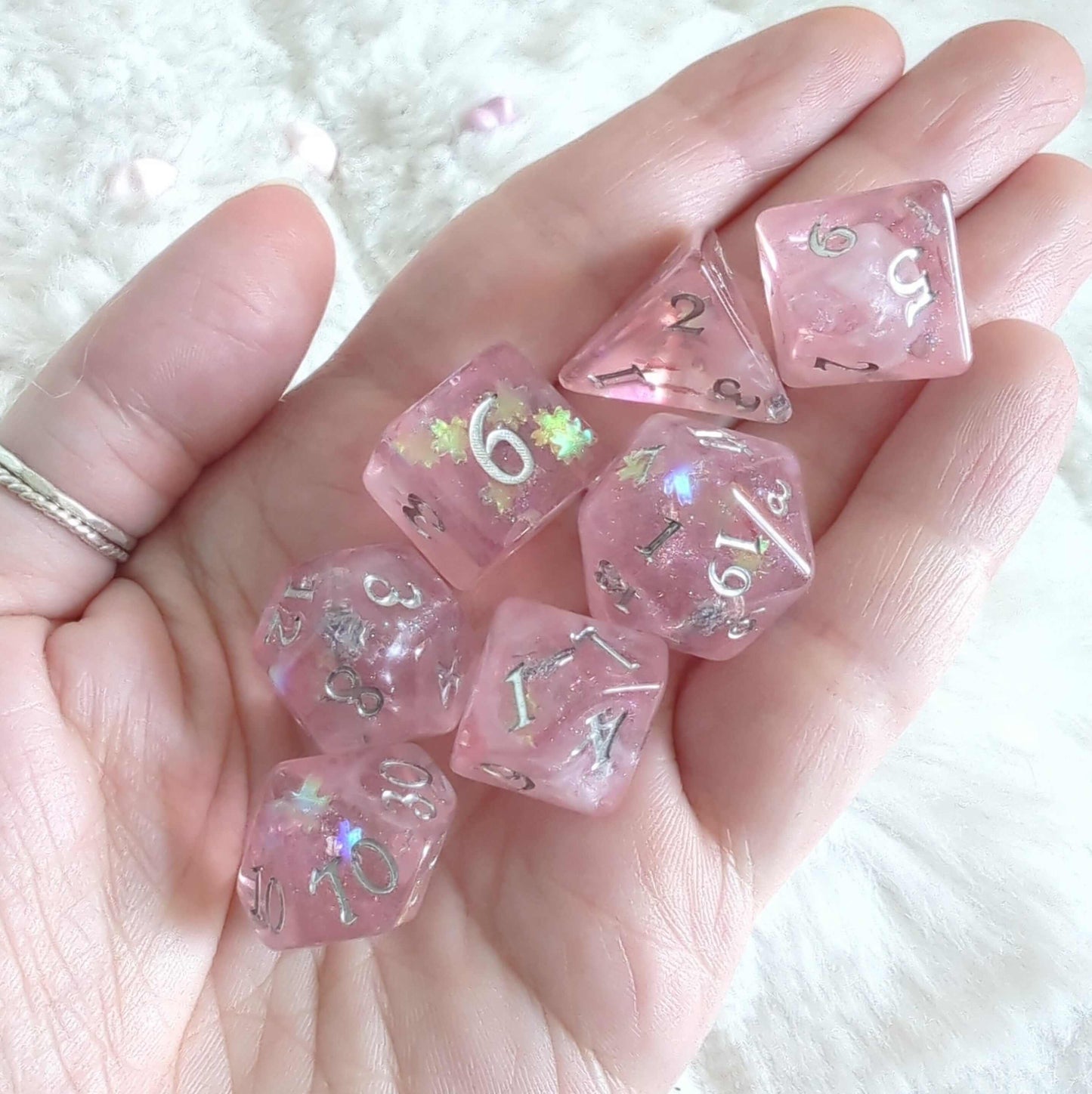 Cherry Blossom Dice Set with pink hue and floral glitter held in hand, showcasing delicate springtime design for TTRPG games.
