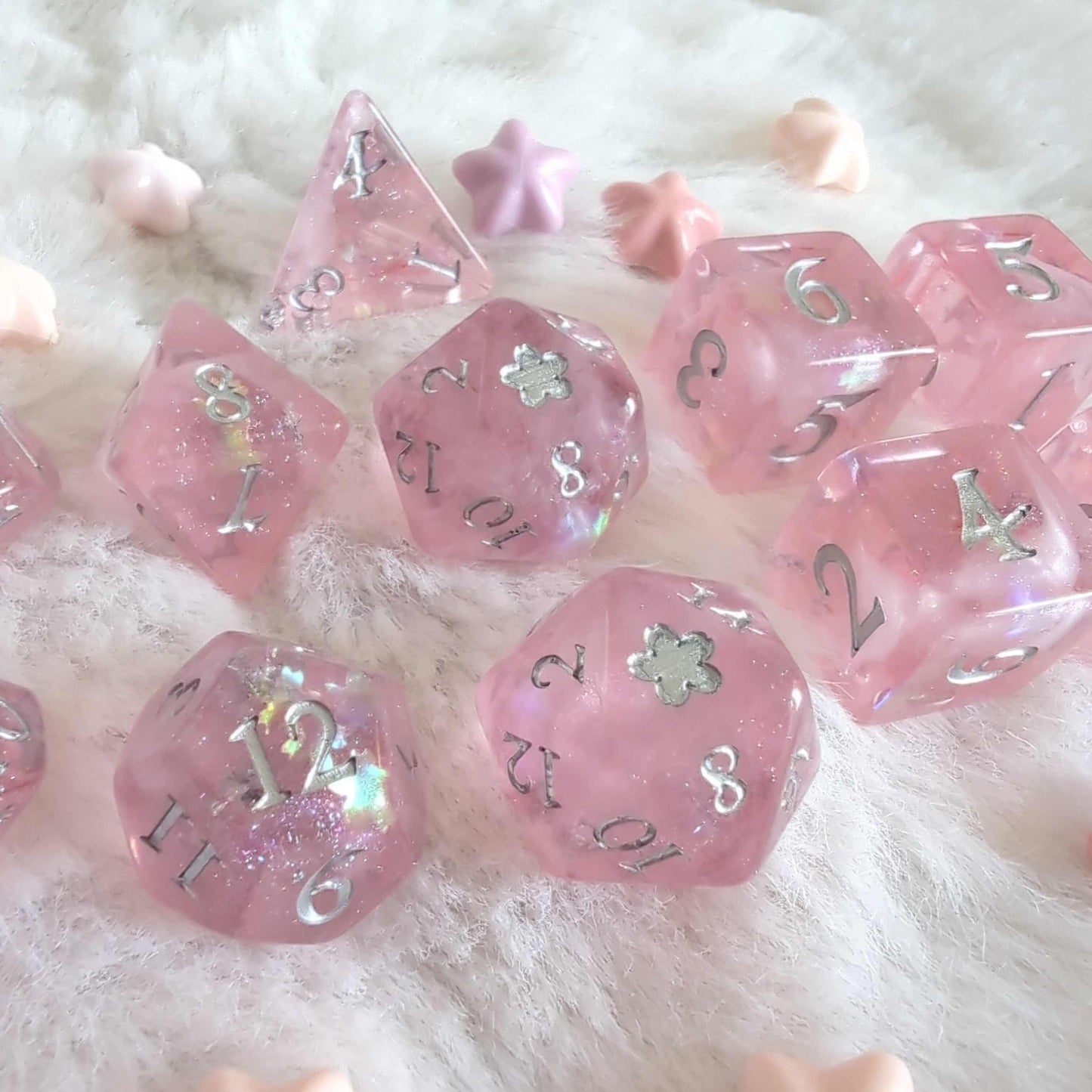 Cherry Blossom Dice Set with pink hue and silver numerals, featuring a D20 with 5-petal flower design and glitter details on soft fabric.