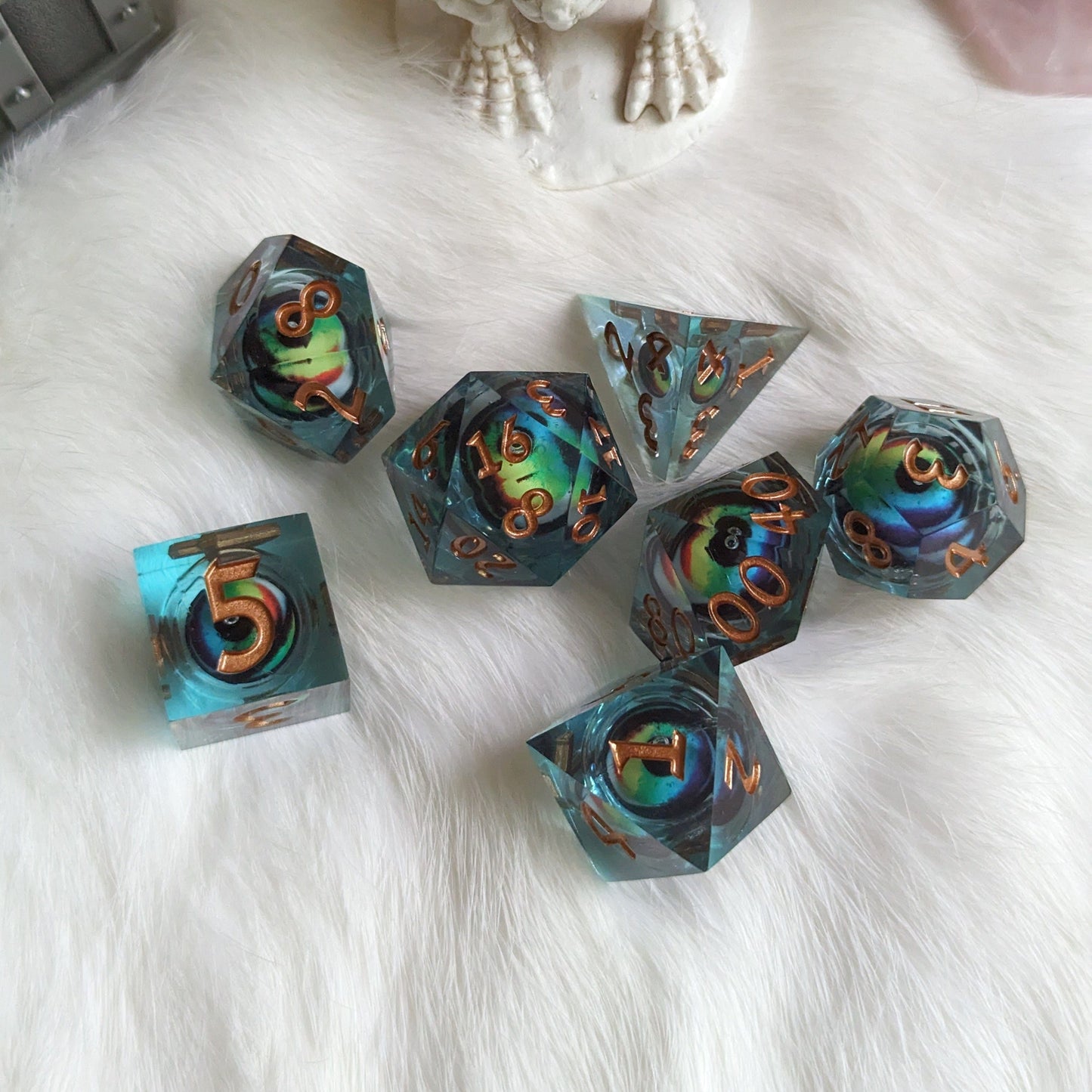 Colorful moving eye liquid core sharp edge resin DnD dice set for tabletop RPGs on white fur background.
