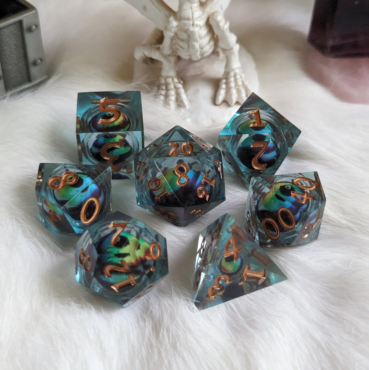 Colorful moving eye liquid core DnD dice set with vibrant swirling colors displayed on a white fluffy surface.