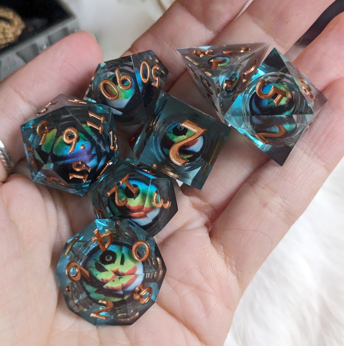 Colorful liquid core dice set with moving eye design for DnD and tabletop RPGs in hand.