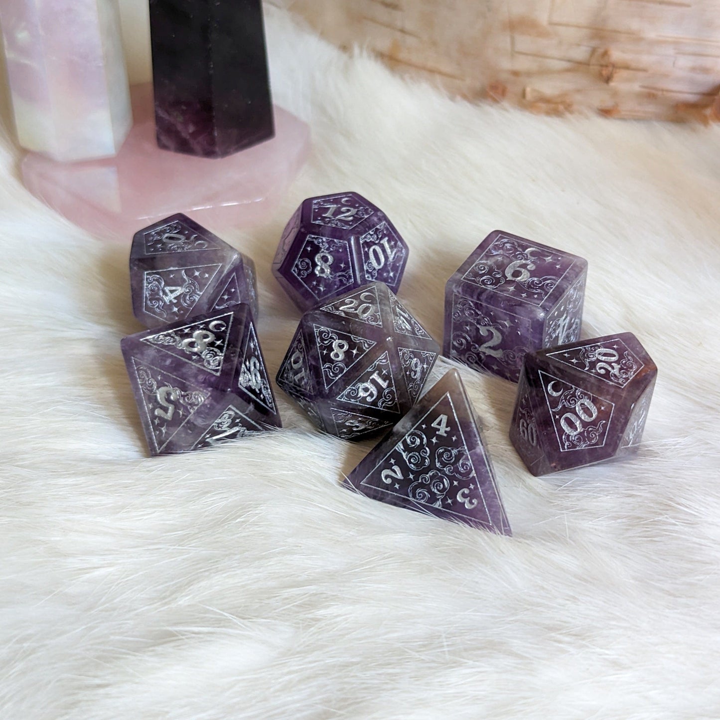 Amethyst gemstone dice set with silver etched stars and moons, designed for tabletop RPGs like Dungeons & Dragons.