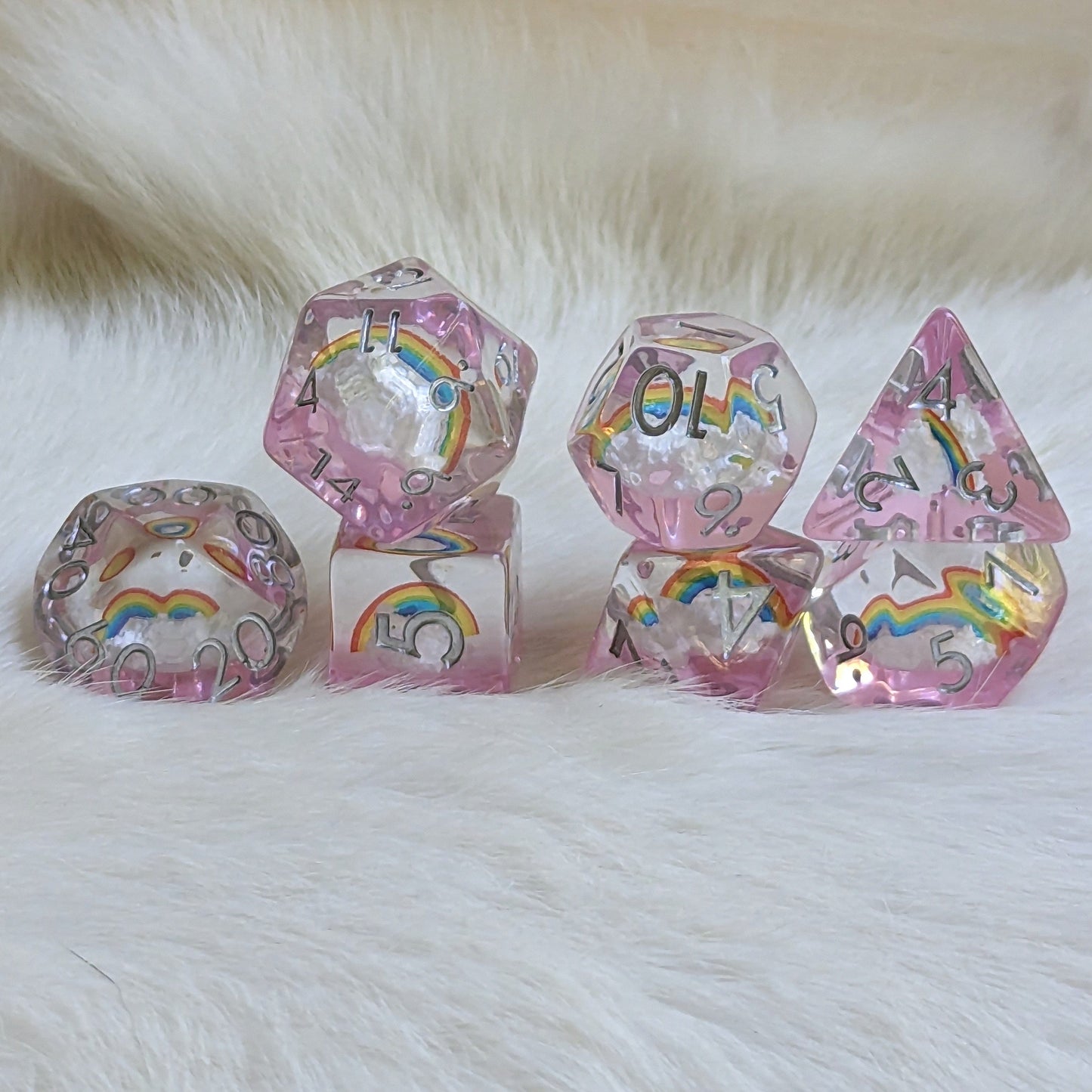 Dreamy Rainbows and Clouds dice set featuring clear resin with cloud and rainbow designs on a light clear purple background.