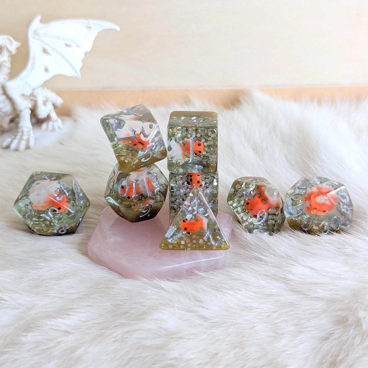 Fancy goldfish in resin with glitter dice set on pink rock, perfect for RPG games like Dungeons & Dragons.