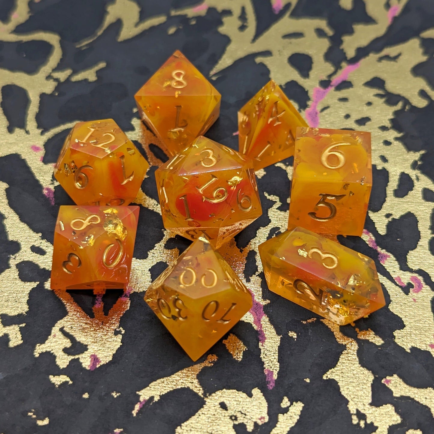 Flame Cast DnD dice set with orange, yellow, and red swirls and gold numbers on a decorative background.