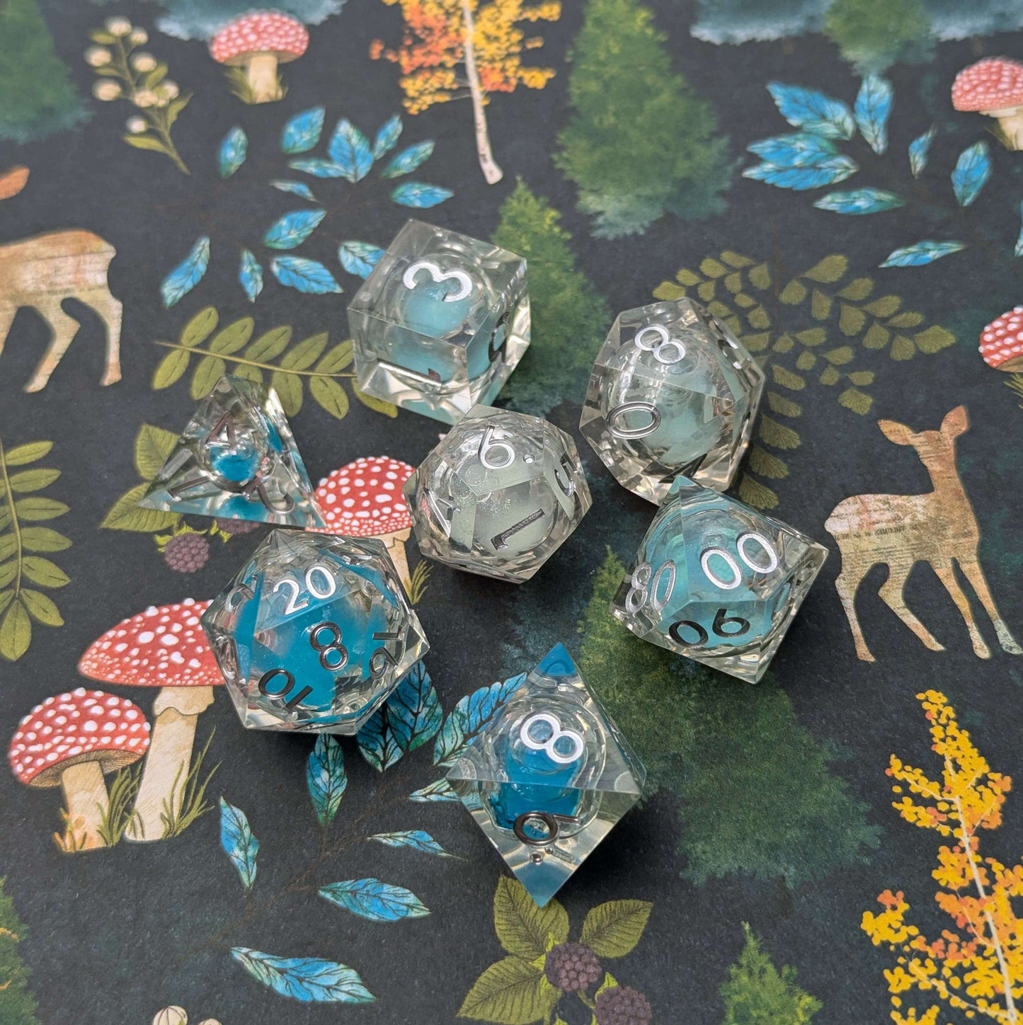 Frostbound Shimmer Liquid Core DnD Dice Set with blue glitter on a nature-themed backdrop.