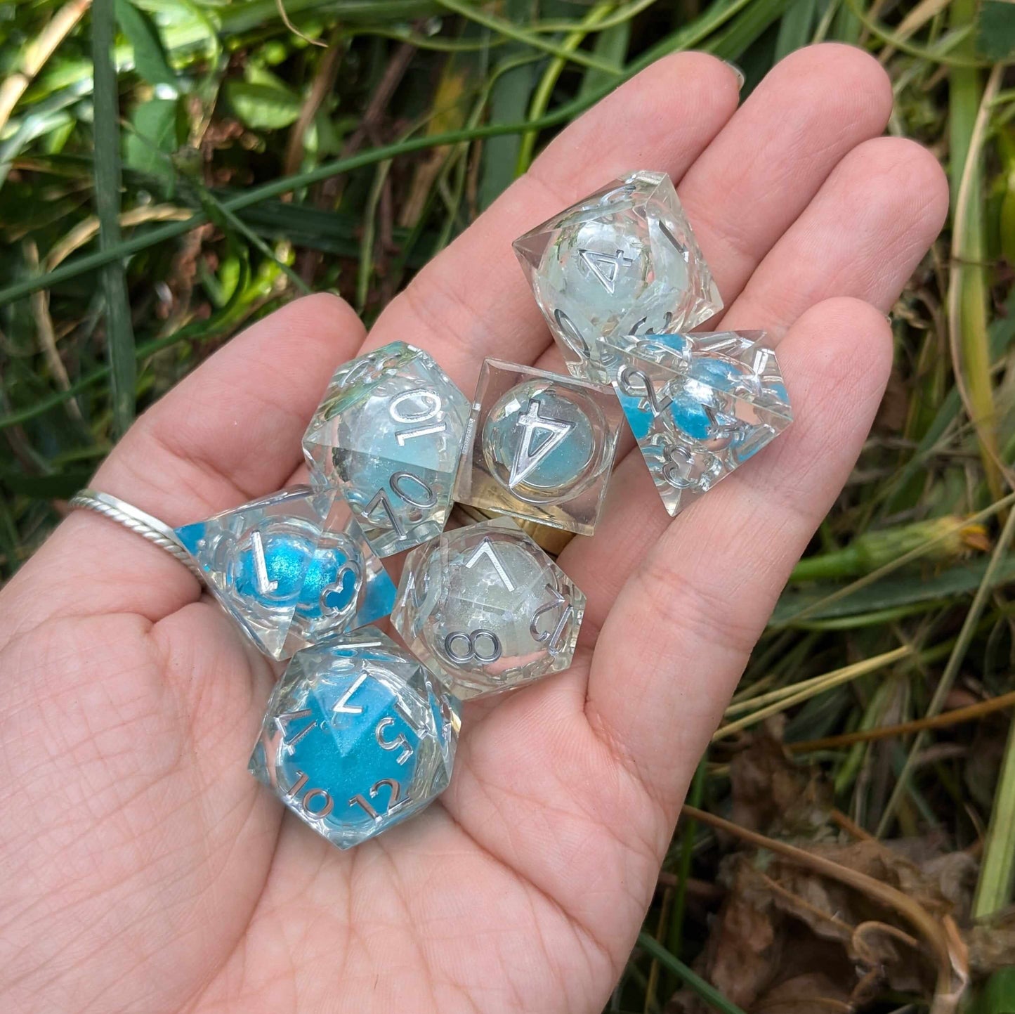 Hand holding Frostbound Shimmer Liquid Core DnD dice set with white-to-blue glitter filled liquid cores and icy elegance.