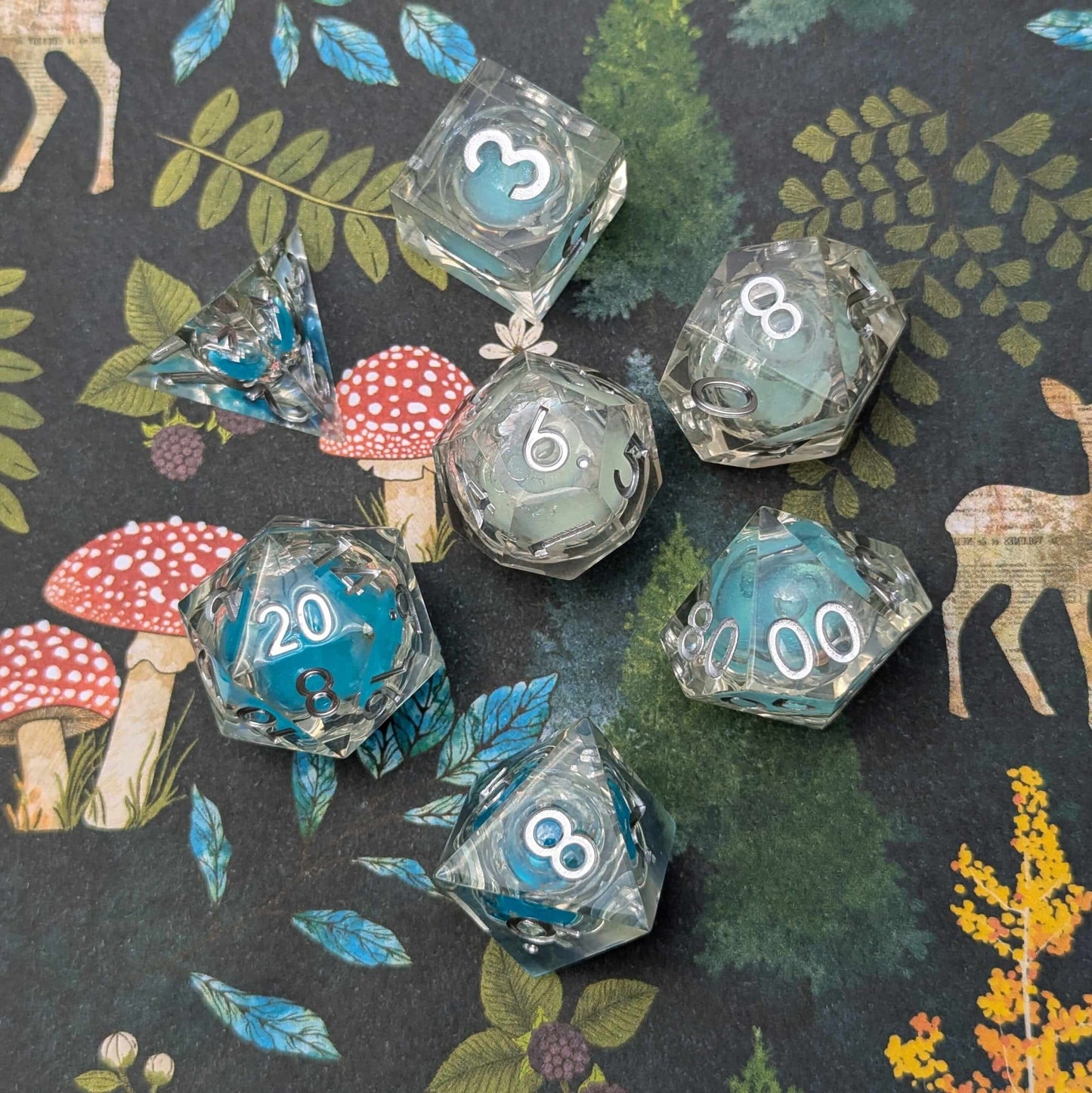 Frostbound Shimmer Liquid Core DnD Dice Set with blue and white glitter on a forest-themed backdrop.