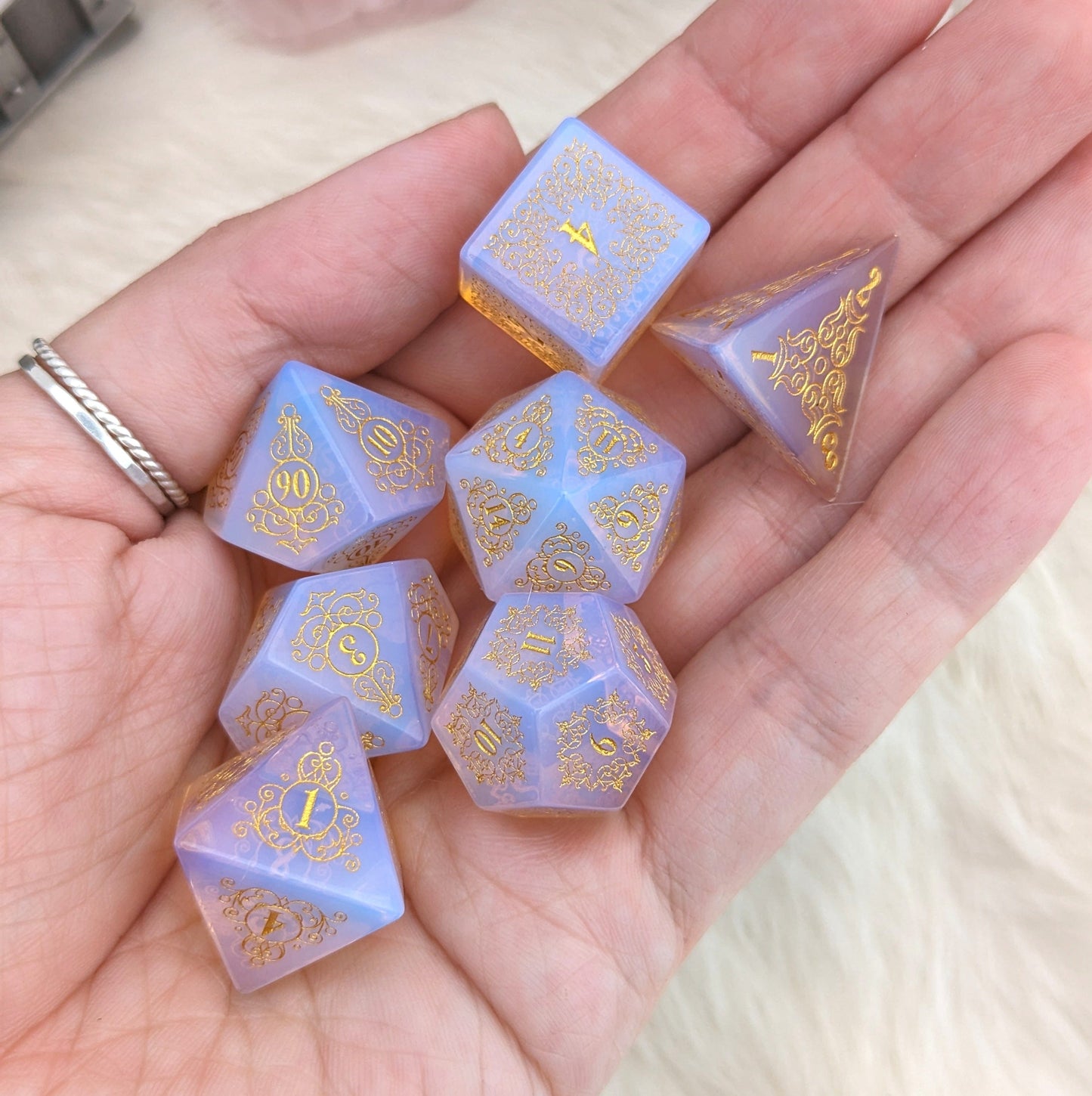 Glowing Pink Opalite Gemstone Dice Set with floral designs on a hand, showcasing intricate Garden Gate patterns.