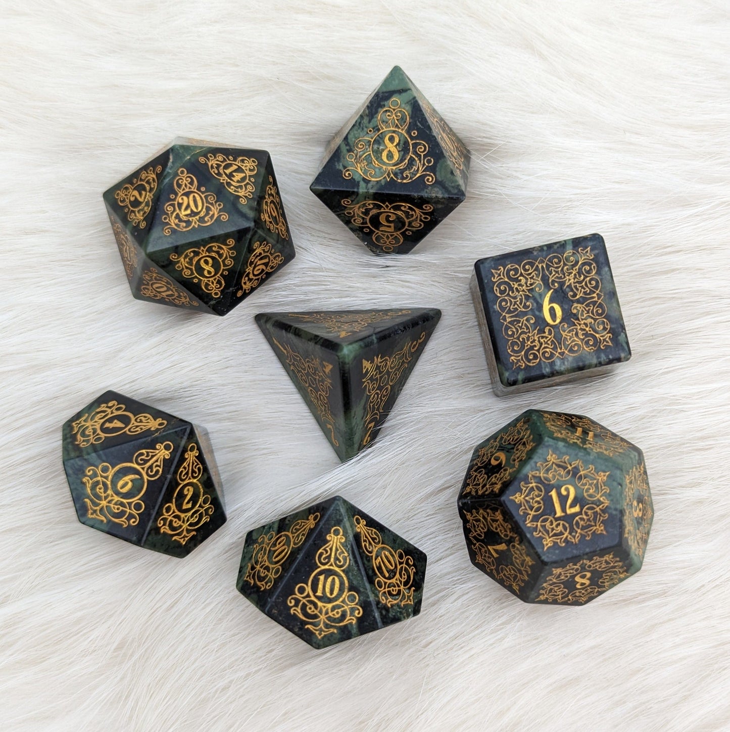 Garden Gate Jasper Gemstone Dice Set with gold floral engravings on green jasper lying on a soft white background.