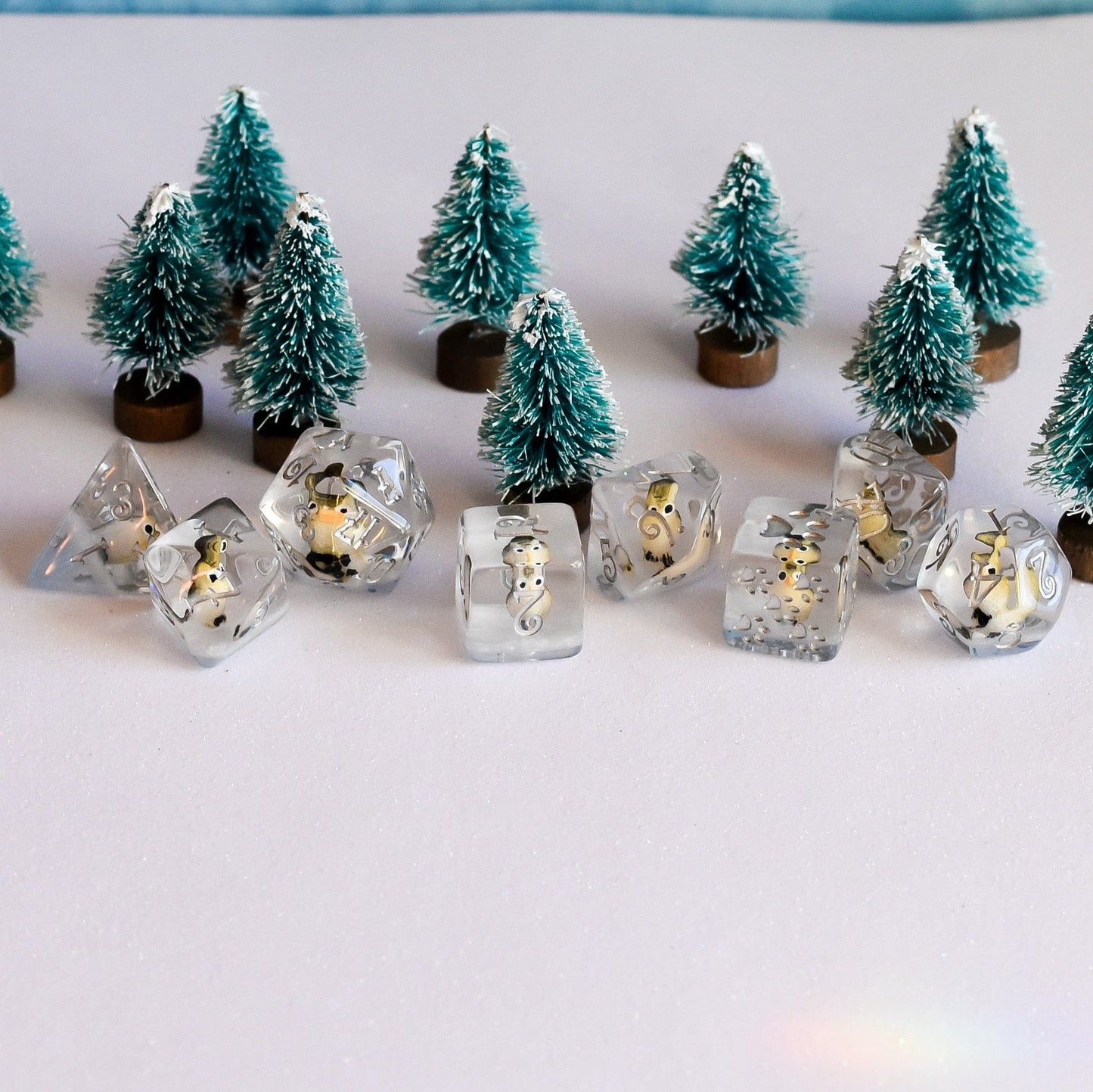 Horned Owl Dice Set with miniature owls in clear resin, surrounded by small pine trees, designed for tabletop games.