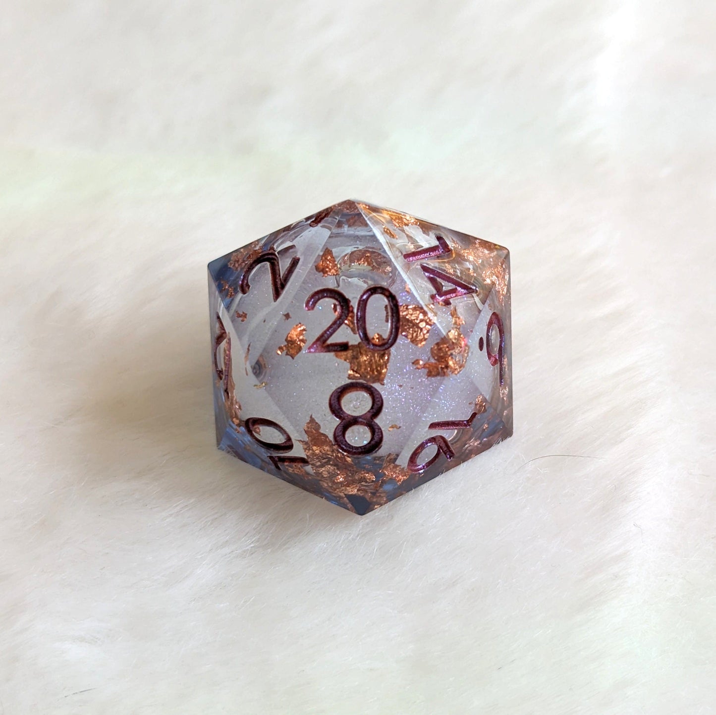 Large liquid core D20 die with swirling glitter, perfect for Dungeons and Dragons and tabletop games, on a soft background.