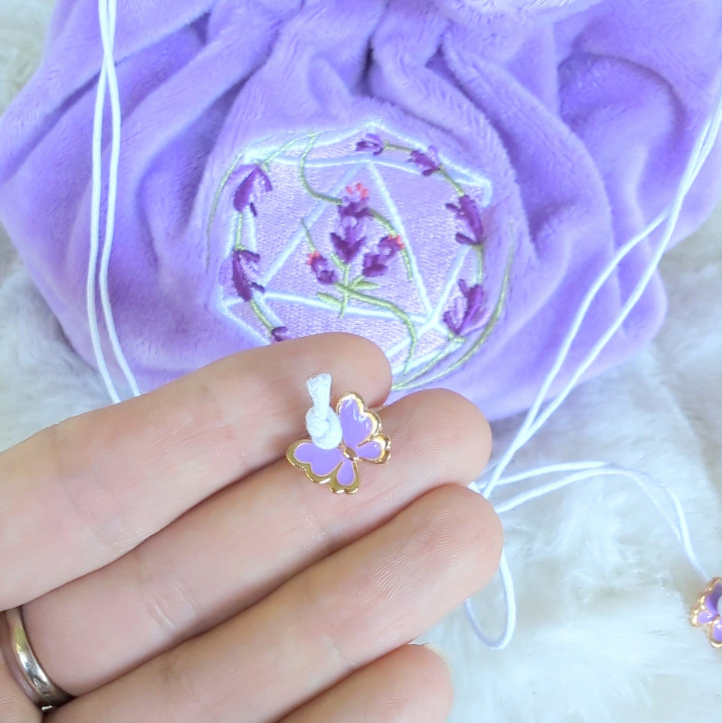Purple dice bag with embroidered D20 and lavender design, featuring drawstring with purple butterfly charm.