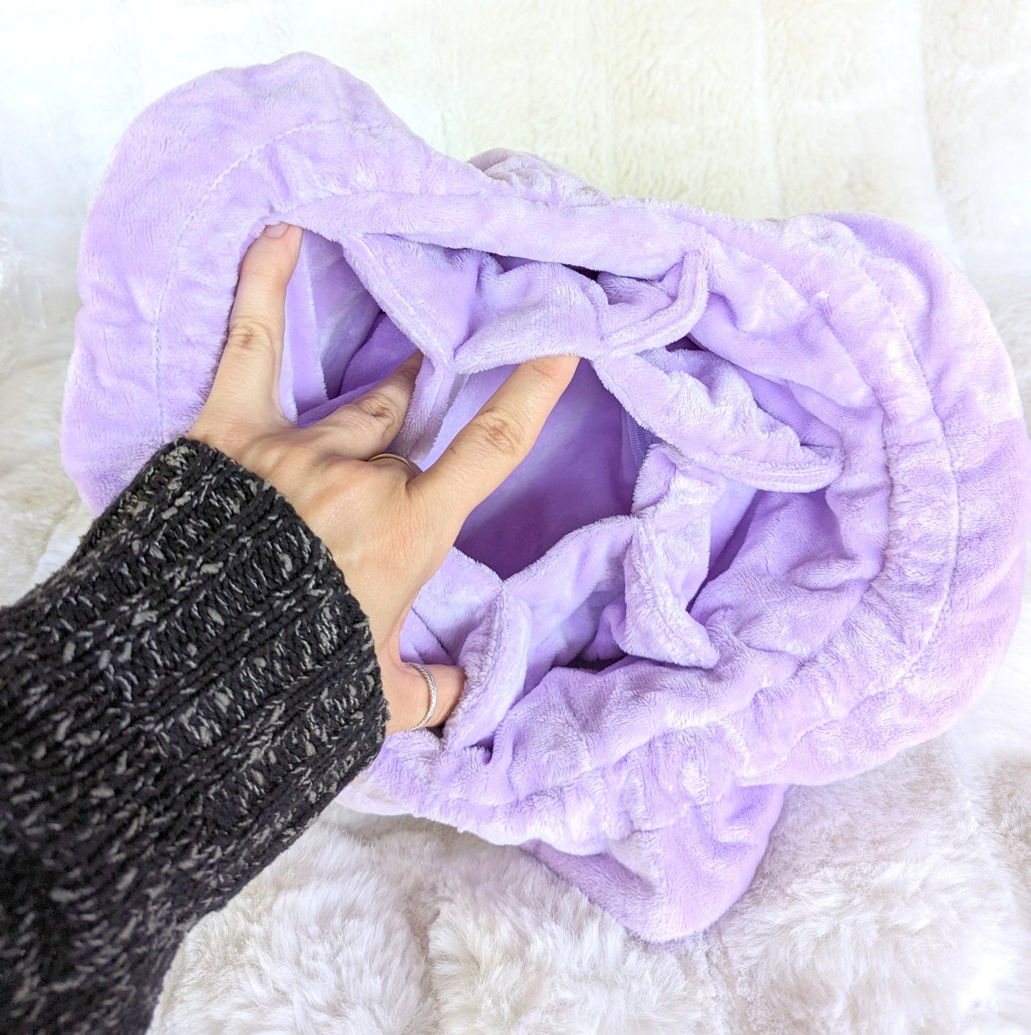 Lavender multi-pocket dice bag with plush purple fabric, open view showing spacious interior, held by a hand with knitted sleeve.