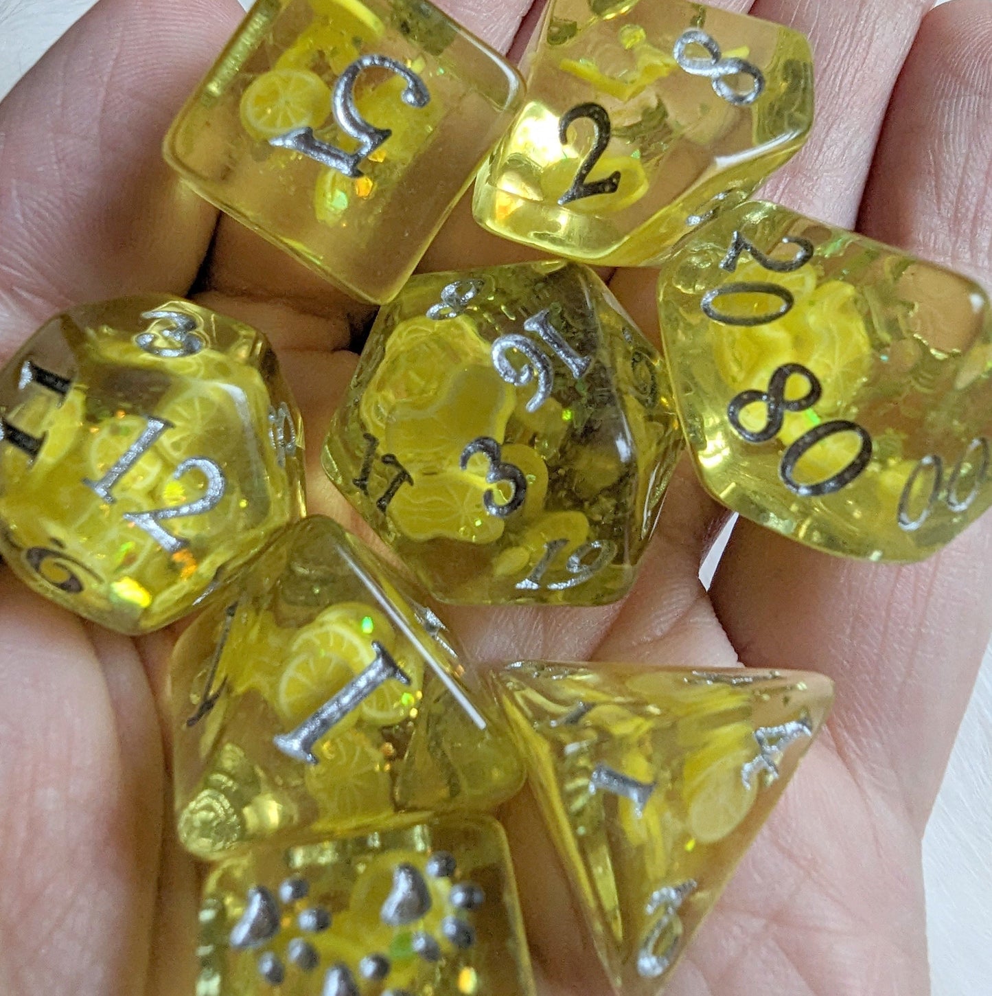 Lemon Dice Set featuring glittery yellow polyhedral DnD dice with lemon slices and paw prints, held in a hand.