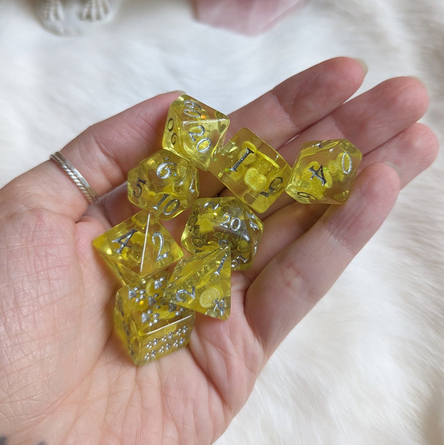 Hand holding the Lemon 8-piece DnD dice set with vibrant lemon slice design and glitter, perfect for tabletop games.