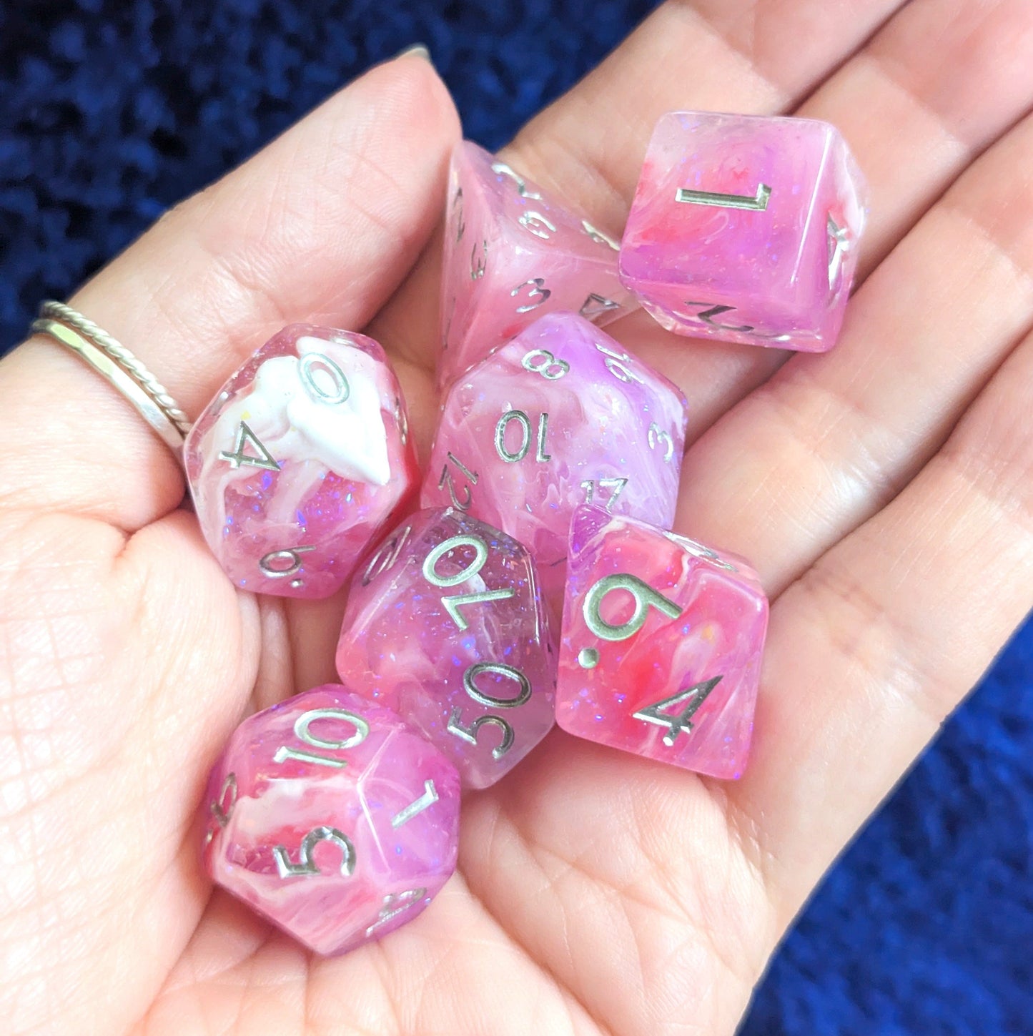 Purple, red, and pink glittering Lover's Enchantment Dice Set for TTRPGs in a hand, perfect for Dungeons and Dragons.