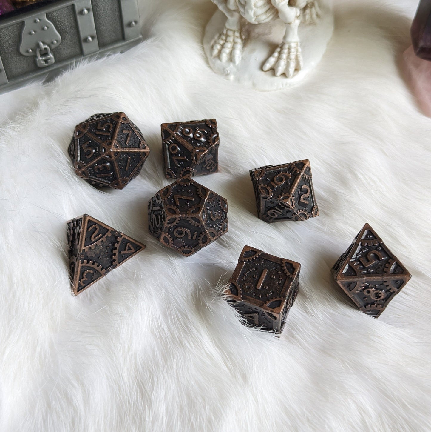 Bronze Metal Gears Dice Set with clockwork design, featuring seven polyhedral dice for tabletop RPGs on a white fur background.