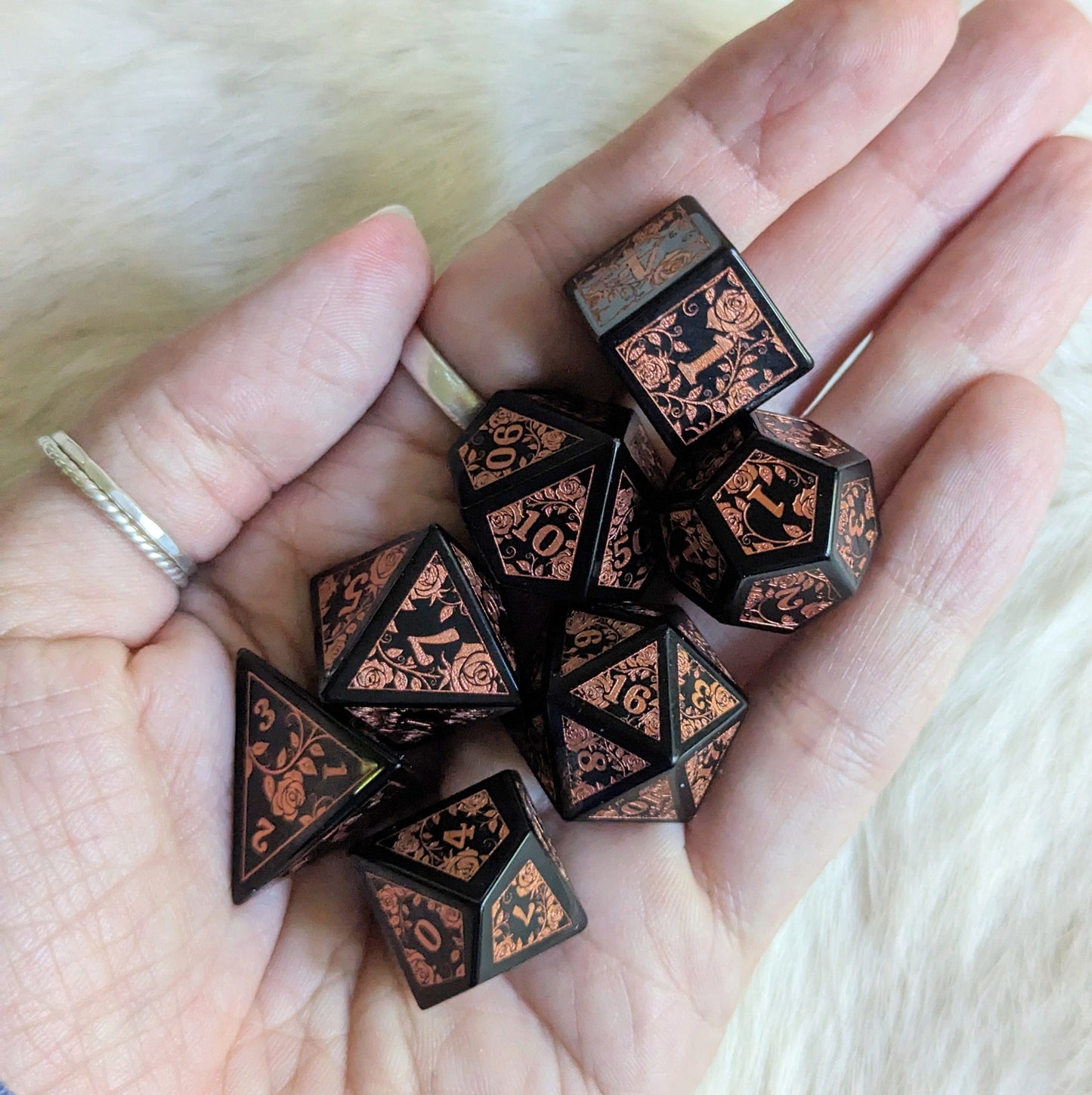 Hand holding Obsidian Rose Dice Set, featuring rose and vine designs in copper on volcanic glass, perfect for Dungeons & Dragons.