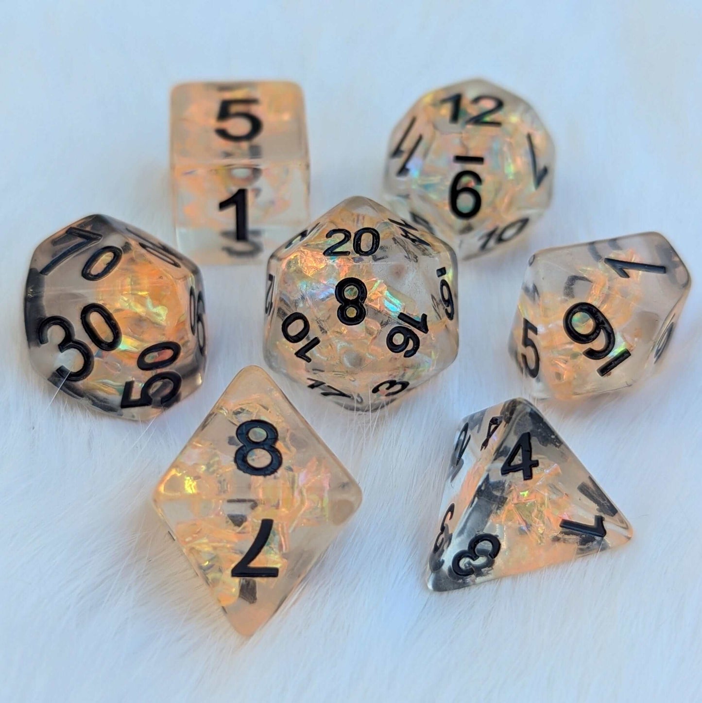 Phoenix's Rebirth TTRPG Dice Set with orange iridescent design on white background, featuring a 7-piece set with bold black numbers.