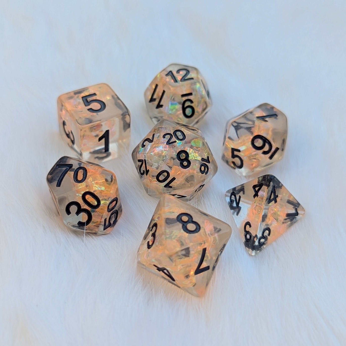 Phoenix's Rebirth TTRPG Dice Set with orange iridescent cellophane, clear resin, bold black numbers, vibrant orange and gold hues.