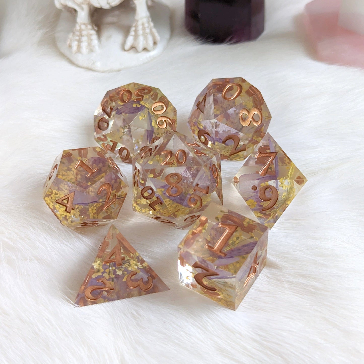 Purple butterfly and yellow flower DnD dice set with copper numbers on a white surface.
