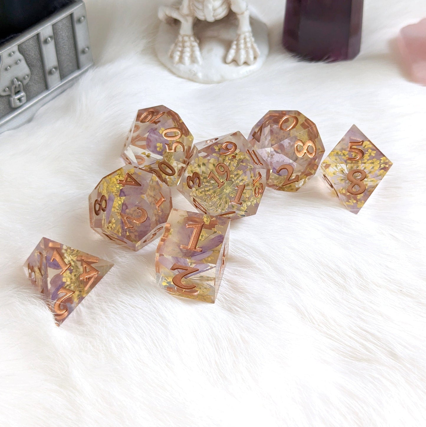 Purple butterfly and yellow flower TTRPG dice set with copper numbers on a white surface.