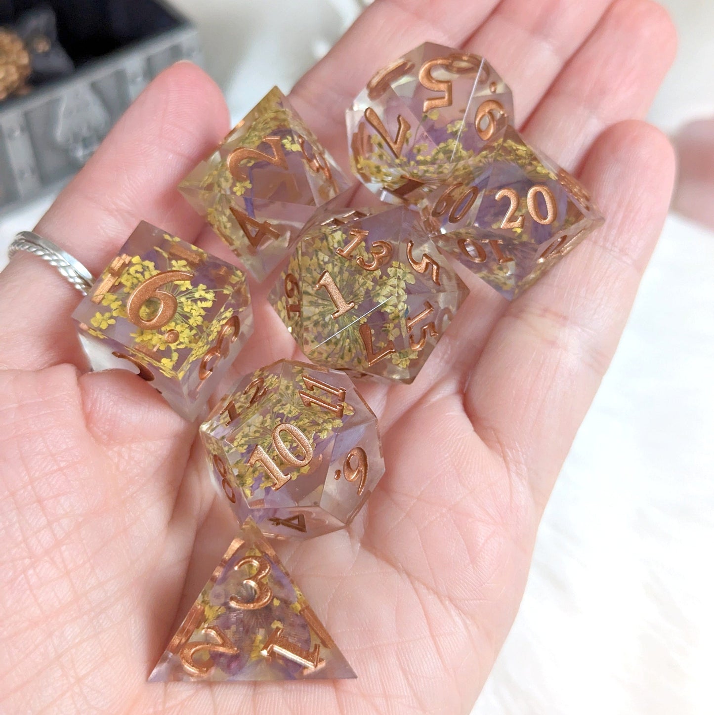 Purple and yellow floral-themed DnD dice set with dried flowers and butterfly inclusions, featuring copper numbers.