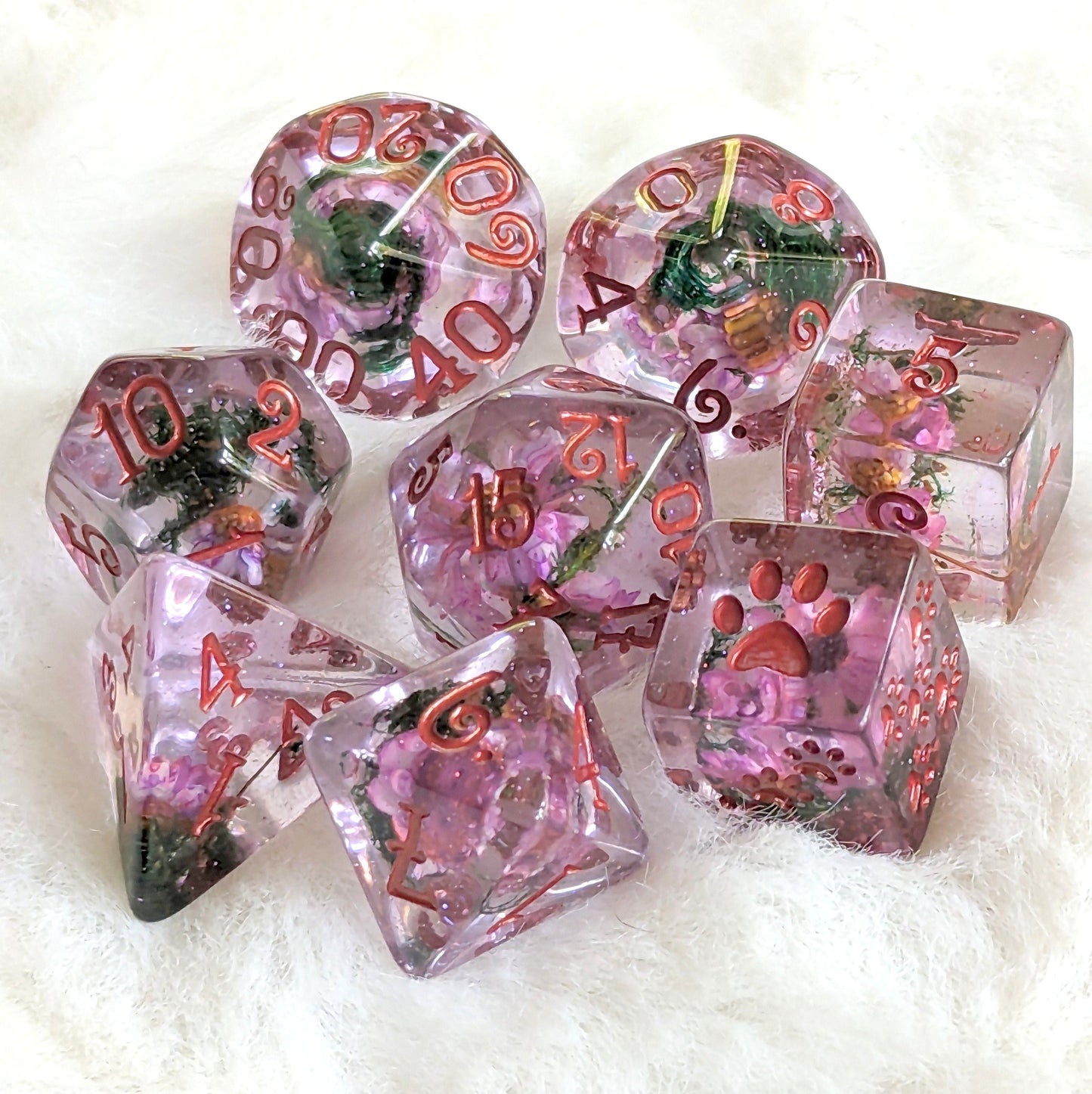 Purple flowers and moss dice set with coppery red numbers, featuring real botanicals and paw counters, laid on soft fabric.