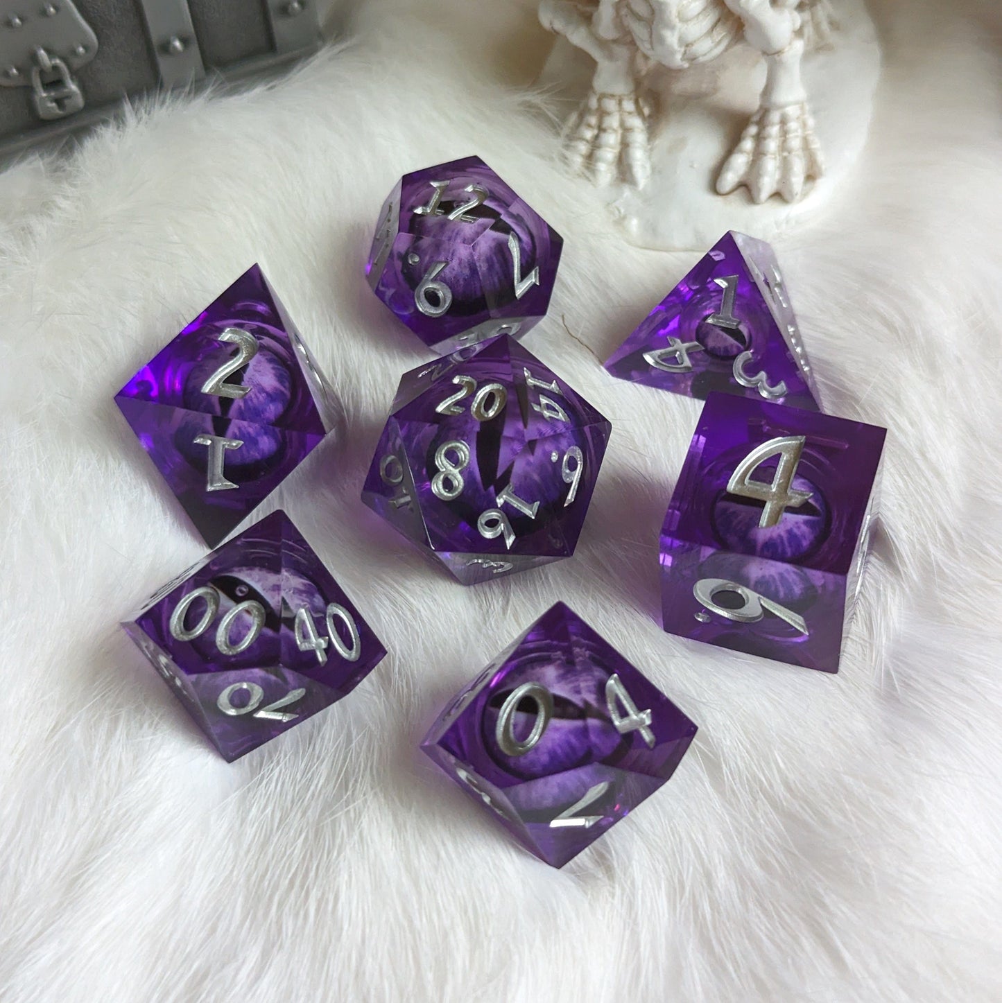 Purple liquid core sharp edge DnD dice set with moving eyes on white fur background.