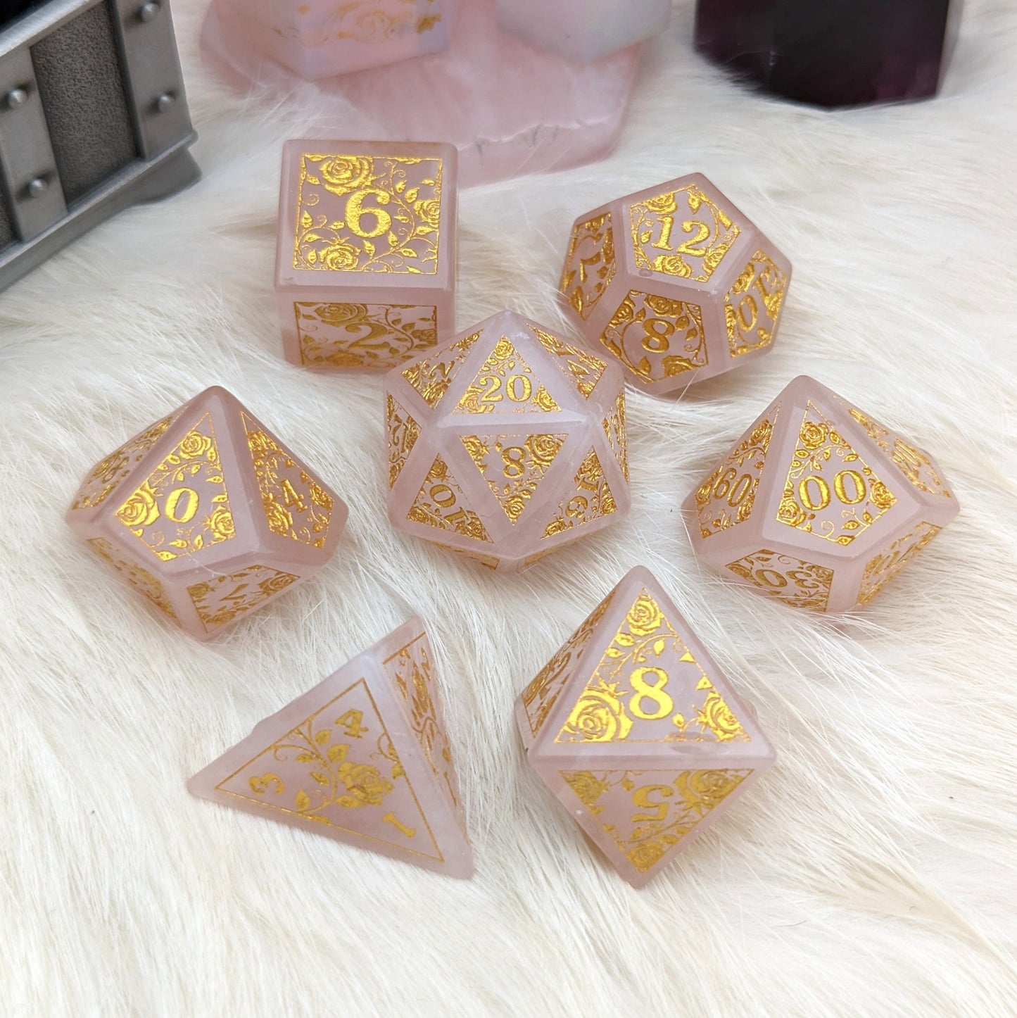 Rose quartz gemstone dice set with golden rose and vine engravings, perfect for Dungeons & Dragons.