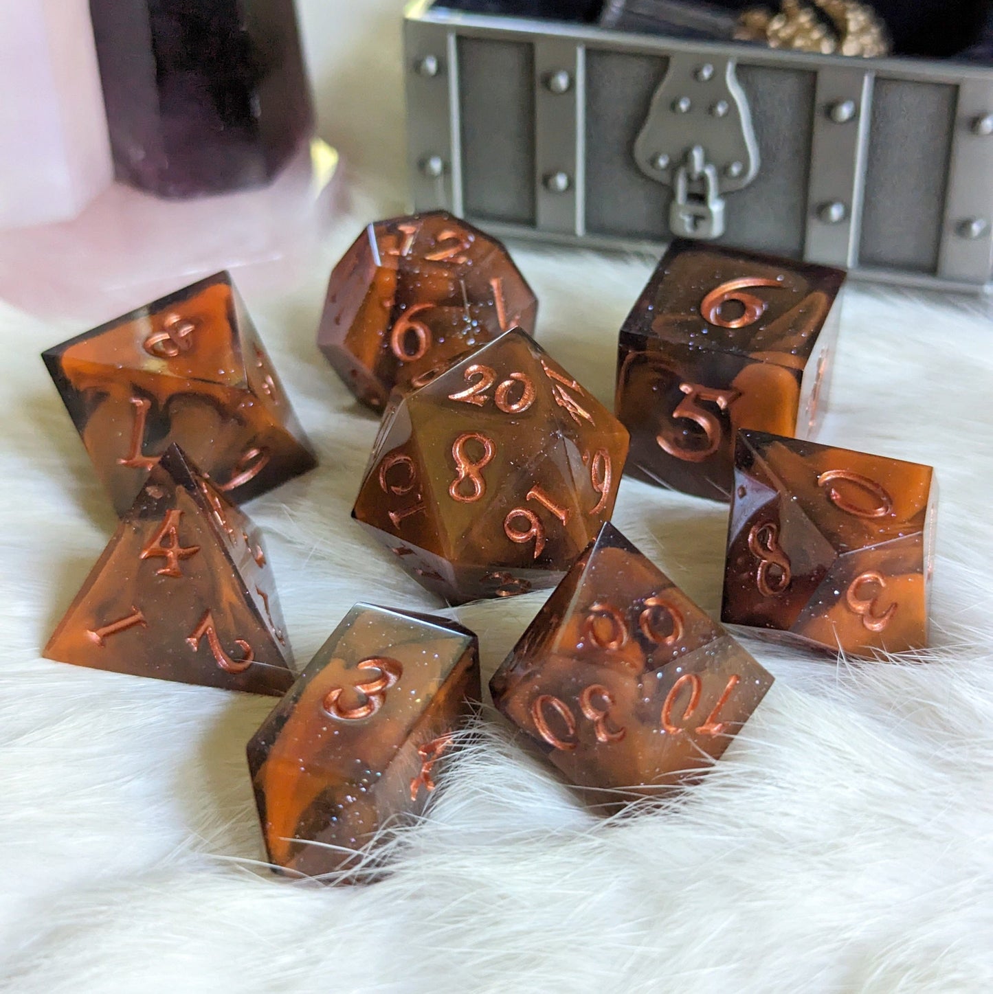Orange and black marble DnD dice set with copper numbers, Shadow and Flame 7 piece TTRPG dice on a white furry surface.