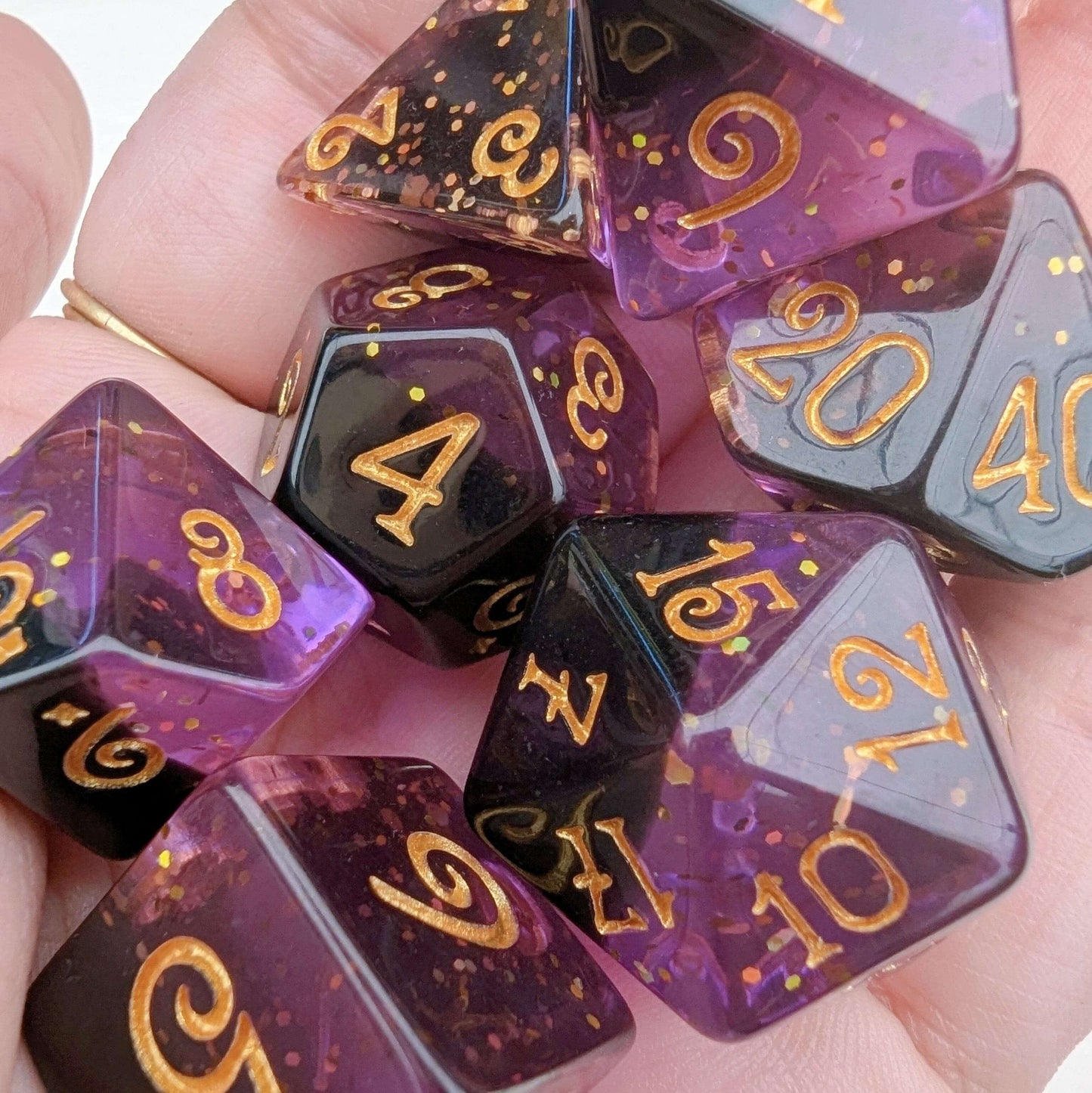 Shadow Magic Dice Set in purple and black with gold glitter, held in hand, showcasing unique layered design and gold numbers.