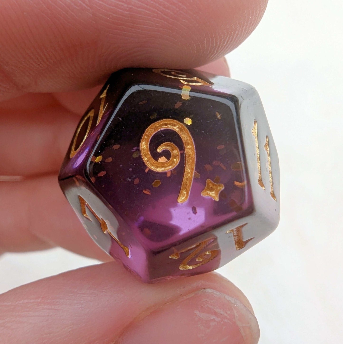 Close-up of a purple and black shadow magic dice with gold glitter and numbers, showing intricate design and custom font.